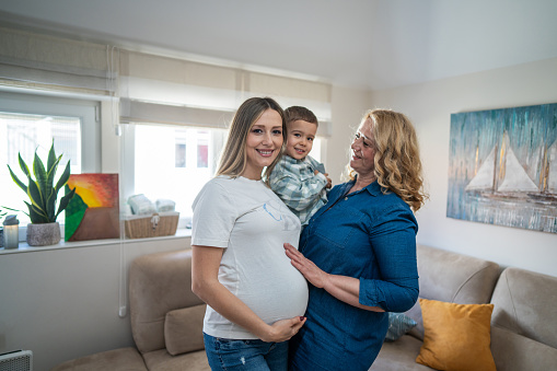 Portrait of happy pregnant woman with mother and son at home