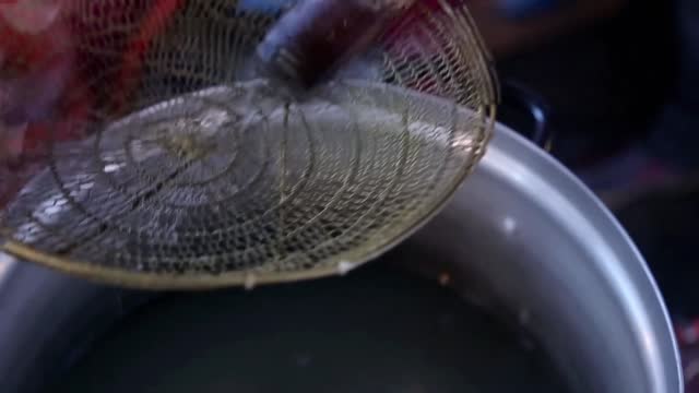 Cooking noodles while stirring using a noodle strainer