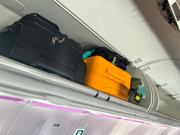 istock Full frame image of overhead baggage compartments with open doors in airplane cabin, row of suitcases, laptop bags and carryon luggage, focus on foreground 2148583747