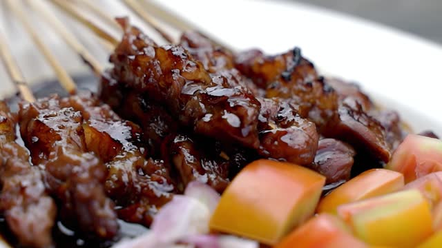 Up close, soy sauce goat satay with tomatoes and red onions, street food