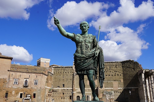February 25, 2024, Rome, Italy. A bronze statue of the Roman Emperor Augustus in front of ancient ruins