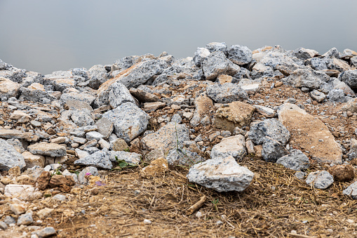 Close-up view: Piles of broken concrete debris taken from road demolition are left on a mound near the edge of a pond, a common sight on farmland in the Thai countryside.