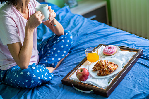 Smiling woman sitting in bed next to her breakfast