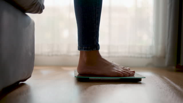 Close-up shot of female' s feet stepping on digital floor scales at home