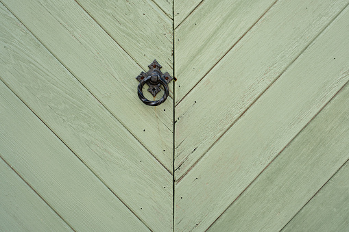 Close-up on a black metal ring on a green wooden gate