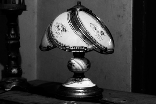 An old fashioned decorative lamp stands on a wooden table