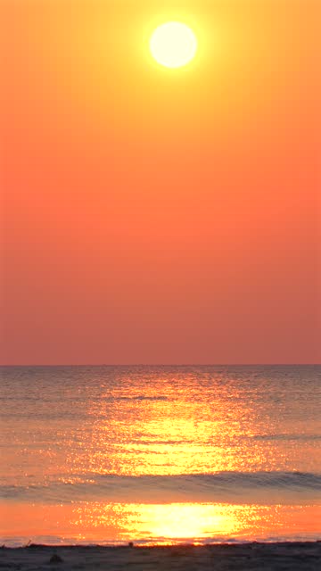 Sunset over ocean with vibrant orange skies reflecting on calm water