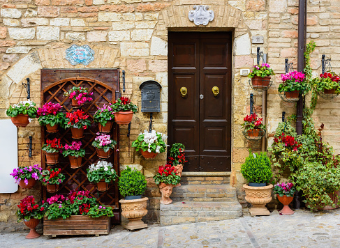 Spello, Italy - March 30, 2023: Close up of a door of a residential building in Spello decorated with colorful flowers. A trip through the small towns of Italy