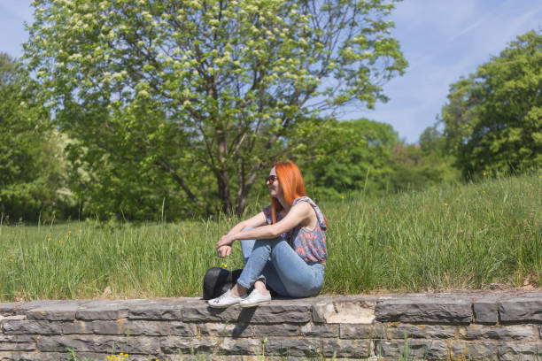 Woman sitting and relaxing at green grass meadow in springtime