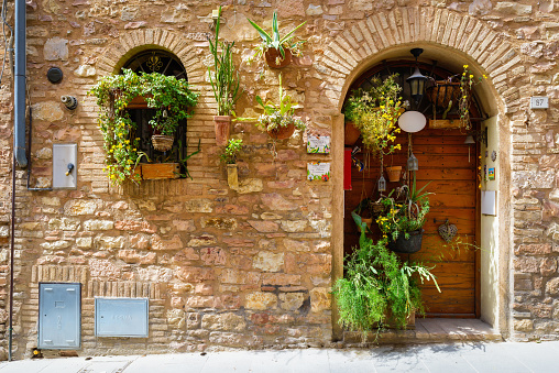 Close up of a door of a residential building in Spello decorated with colorful flowers. Beautiful old streets medieval town Spello, Umbria, Italy. A trip through the small towns of Italy
