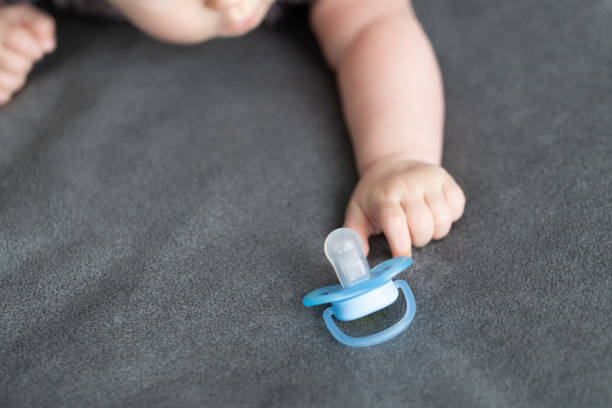 istock Baby's hand stretching to reach the blue pacifier. 2148597841