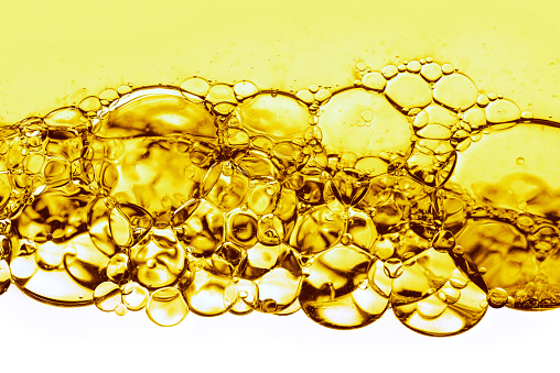 Hydrophilic oil close-up, bubbles in the yellow liquid. Cosmetic essence, Hydration skin care with oils, serum. Oil in water