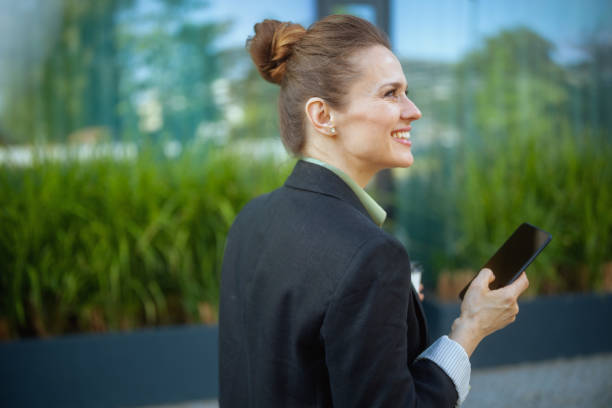 istock smiling female employee in business district using smartphone 2148597893