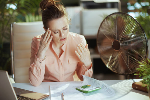 istock unhappy modern female worker at work with electric fan 2148597929