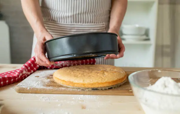 Removing cake base from a baking pan or cake pan by woman´s hands in the kitchen.