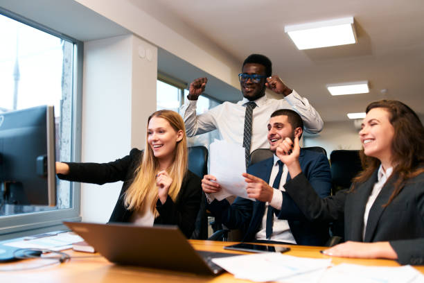 istock Multiethnic business team in office, jubilant at computer screen success. Cheerful diverse colleagues with laptop enjoy corporate victory. Excited mixed group, male, female, celebrate project win. 2148599632