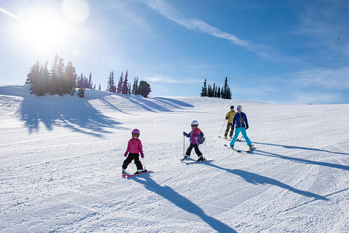 Family skis down slope at Canadian ski resort on a sunny winter day