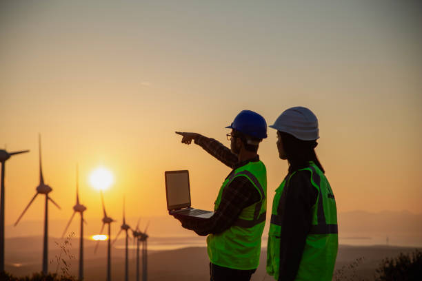 istock Young maintenance engineer team working in wind turbine farm at sunset 2148602960