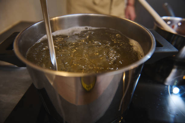 Close-up stainless steel pan with boiling water for spaghetti or other meal on the black glass surface of an electric stove