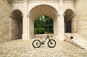 Freestanding mountain bike against the backdrop of architectural arches. MTB cover concept