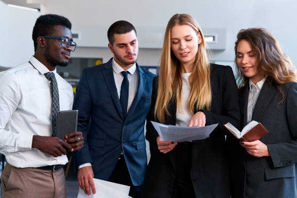 istock Multiethnic corporate team collaborates in office setting, reviewing documents, strategy planning. African, caucasian, asian execs engage in group discussion for project success. Focus on teamwork. 2148604708