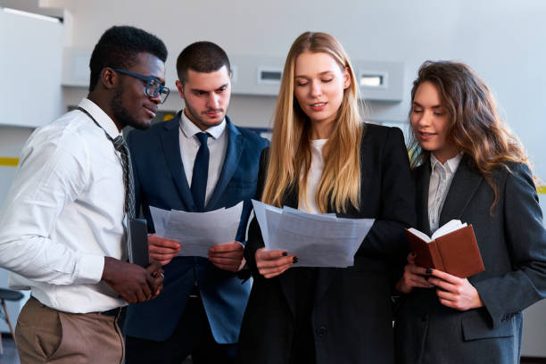 istock Multiethnic corporate team reviews project details. African, Caucasian, Arab execs engage in discussion. Hands hold papers, planner, in office setting, exemplifying collaborative planning, leadership. 2148604750