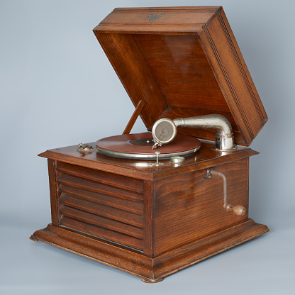 vintage gramophone with 78 rpm record and metal needle in studio isolated on grey background