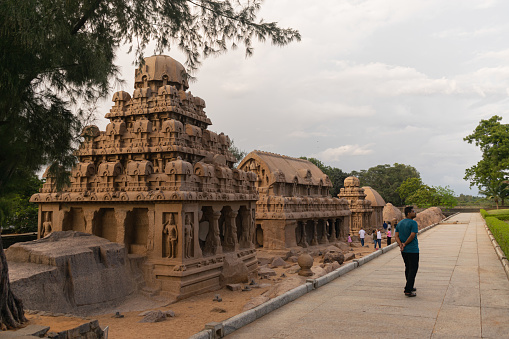 Picture of five rathas and a tourist roaming around on an evening at UNESCO world heritage site of Mahabalipuram. Ajanta, Ellora, Hampi ancient stone sculpture carvings sacred pilgrimage archeology