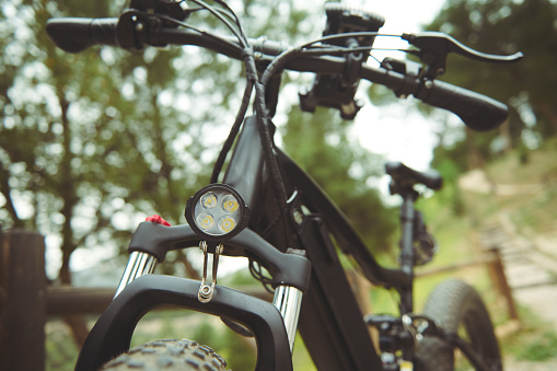 Cropped view of modern ecologically friendly mode of transport - electric bike bicycle, motor bike on the nature outdoors. Bike sharing city service. Environmental conservation. Sustainable lifestyle