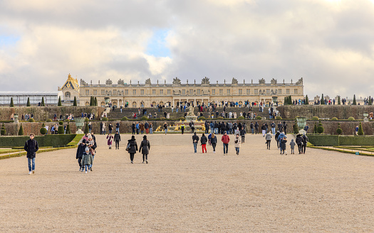 Chateau de Versailles, Versailles, France - December 28, 2023:  Tourists in the Gardens of the Chateau de Versailles in a cloudy morning.  HDR encoded.