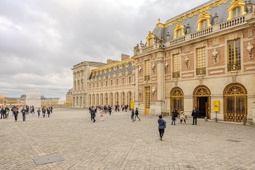 Chateau de Versailles, Versailles, France - December 28, 2023:  Tourists in the Royal Courtyard (Cour Royale) of the Chateau de Versailles in a cloudy morning.  HDR encoded.