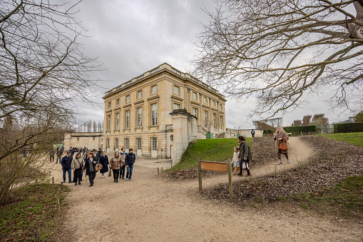Chateau de Versailles, Versailles, France - December 28, 2023:  Tourists walking outside of Petit Trianon on a cloudy day.  HDR encoded.