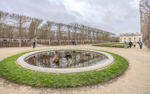 Chateau de Versailles, Versailles, France - December 28, 2023:  Tourists in the French Garden of the Chateau de Versailles on a cloudy day.  HDR encode
