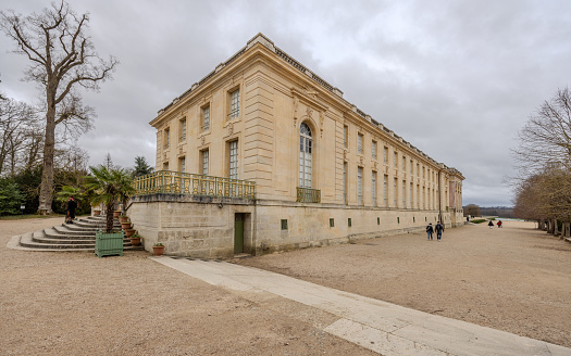 Chateau de Versailles, Versailles, France - December 28, 2023:  Tourists walking outside Grand Trianon of the Chateau de Versailles on a cloudy day.  HDR encoded.