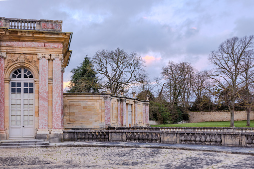 Chateau de Versailles, Versailles, France - December 28, 2023:  Grand Trianon of the Chateau de Versailles in a late cloudy afternoon, with some golden clouds from setting sun.  HDR encoded.