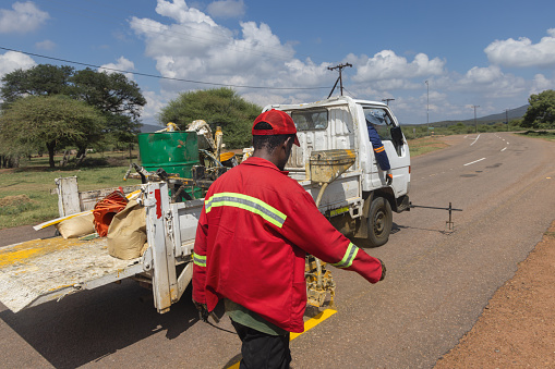 african men repairing and maintaining faded road markings on the highway, repainting yellow markings for traffic safety