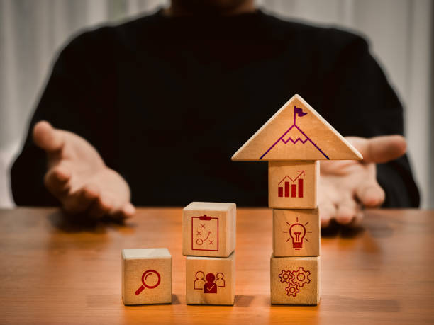 istock Business strategy, target goal mission building, leadership, organizational development plan concepts. mountain peak with flag icon on wood cubes stack with strategic symbols arranged by businessman. 2148607999