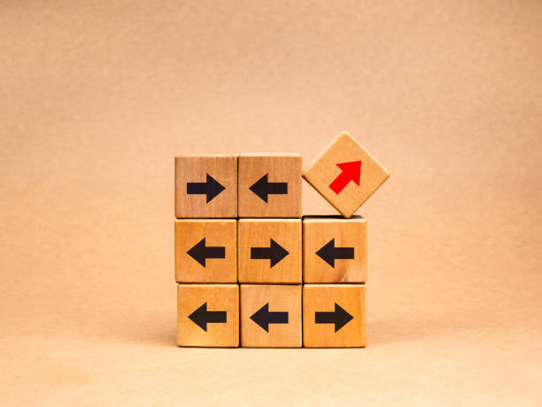 istock Leadership, unusual, odd, unique, think different way and stand out from the crowd concepts. Red arrows go up diagonally and black arrows indicate directional vignettes on wood cube blocks stack. 2148608008