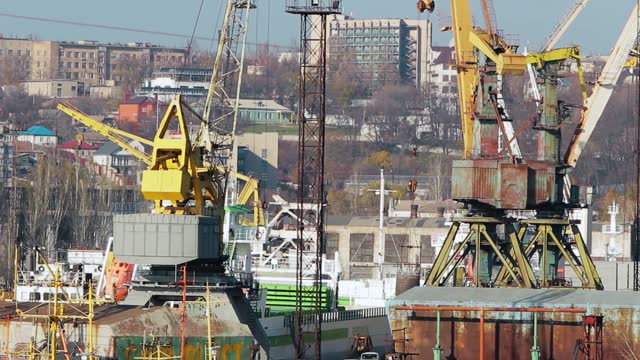 Historic Azov shipyard in Mariupol showcases sprawling docks, towering cranes, maritime construction. Clip reveals industrial vessel assembly, heavy machinery, urban backdrop economic vigor.