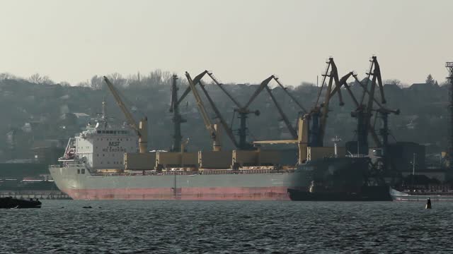 Historic Azov shipyard footage shows cargo ship docked, cranes lining port in Mariupol. Industrial maritime operations, shipping logistics. Historical seaport activity, trade routes highlight