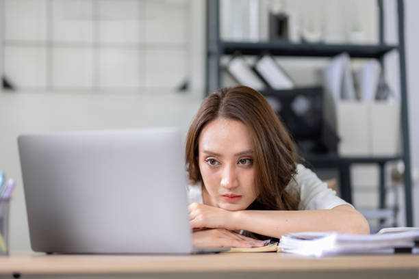 istock Businesswoman looks stressed, bored and holding her head. Indicates a headache while working at a desk in home office. 2148609845