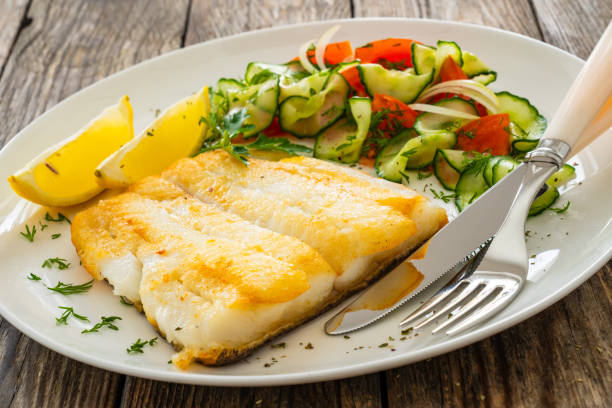 istock Fried halibut fillet and fresh vegetables on wooden table 2148610666
