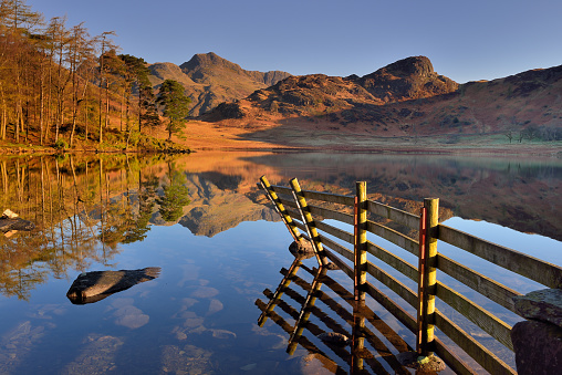 Dawn at Blea Tarn with the Langdale Pikes reflected in the still surface of the water.