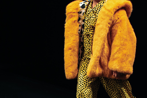 Bright yellow kid's fancy winter fur coat outfit. Fashionable look. Side view