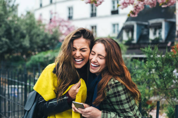 Best friends in Paris laughing and texting
