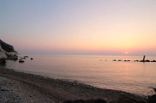 Horizon of the Mediterranean Sea photographed at summer dawn from the Monte Conero beach. Sirolo, Marche, Italy.