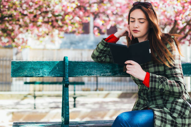 istock Beautiful woman sitting at bench and reading an e-book 2148613922