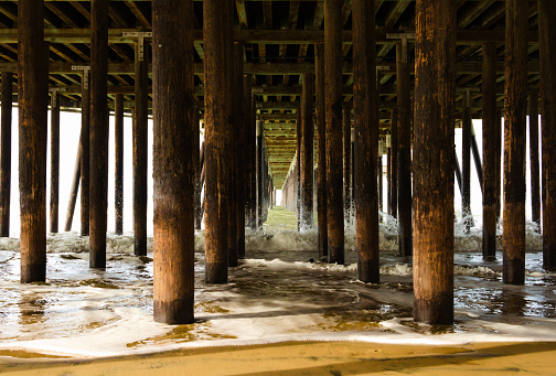 Waves crash into wood pilings holding up the 1200 foot Pismo Pier at Pismo Beach, California