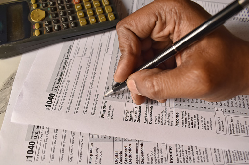A closeup picture of a person filling the form 1040 with a black pen. US tax form.