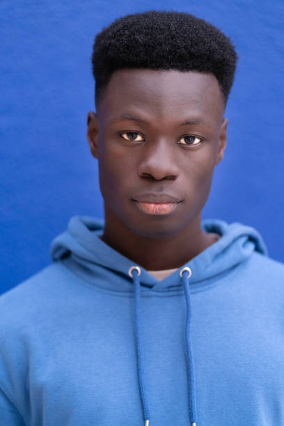 A man wearing a blue hoodie is making direct eye contact with the camera.